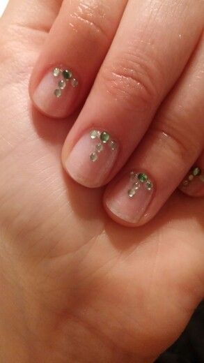 Sophisticated Minimalist Nude Nail Design Accentuated with Sparkling Green Rhinestones.