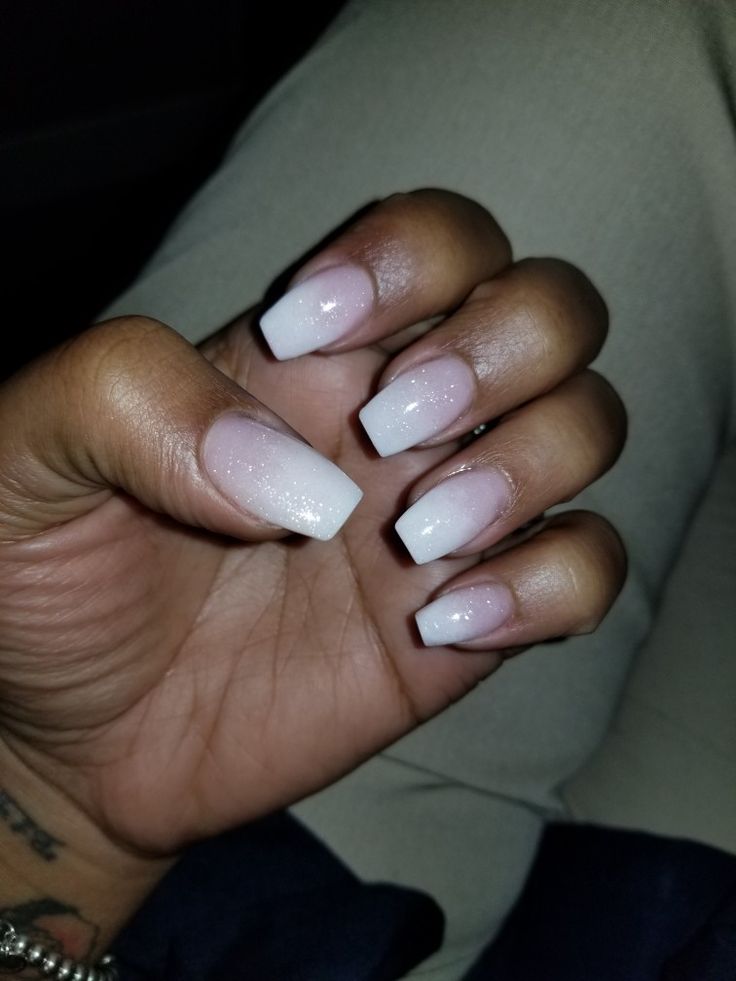 Elegant Ombre Nail Design: Soft White to Pink Gradient with Sparkling Accents and Modern Squared Tips.