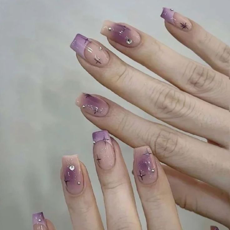 Elegant Gradient Purple Nail Design with Whimsical Hand-Painted Patterns and Gem Accents.