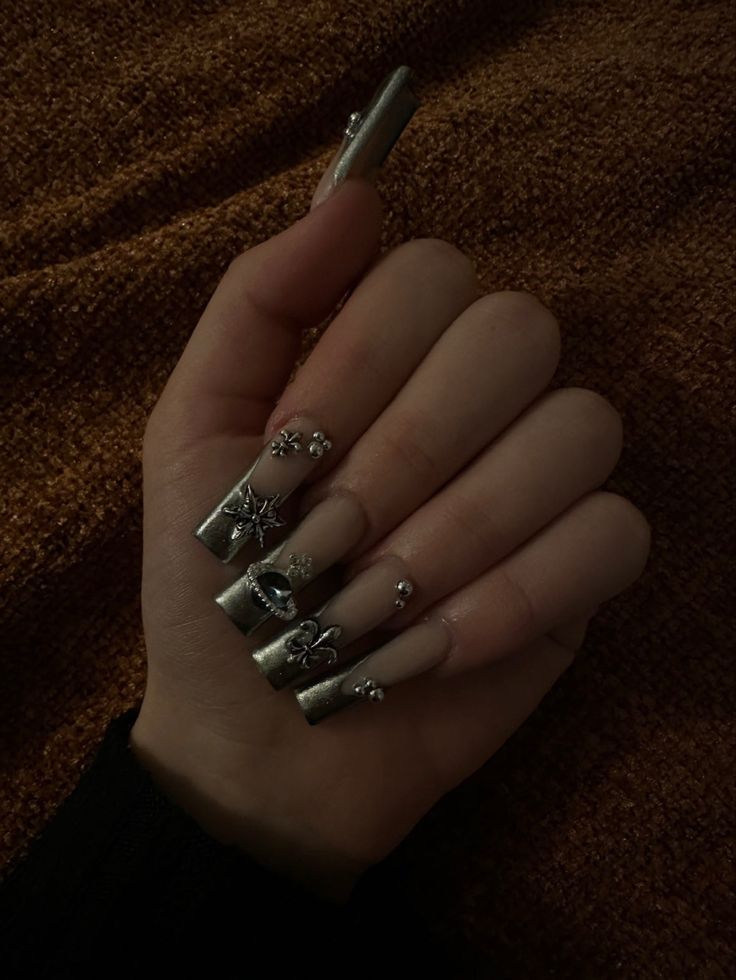 Glamorous Metallic Silver and Nude Nail Design with Intricate Floral Embellishments.