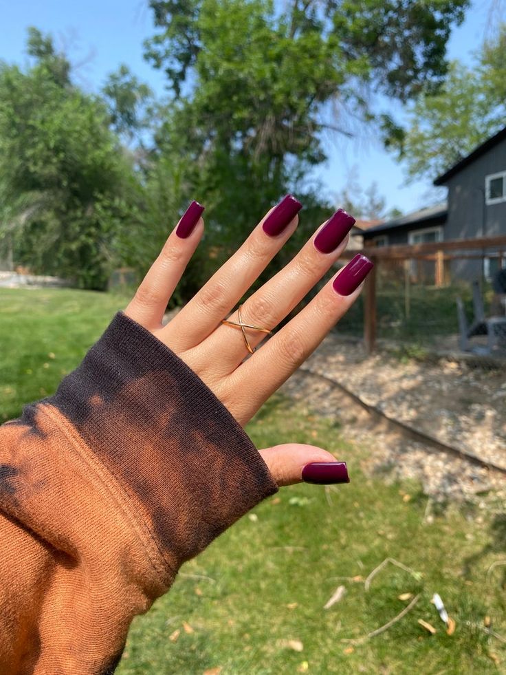 Chic Elegance: Deep Burgundy Matte Nails Complemented by a Gold Ring and Tie-Dye Sweater.