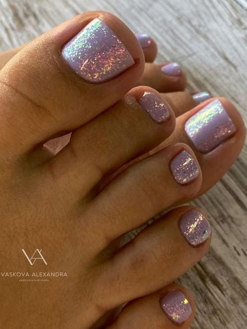 Elegant Sparkling Lavender Toenail Design with Iridescent Accents for Chic Summer Style.