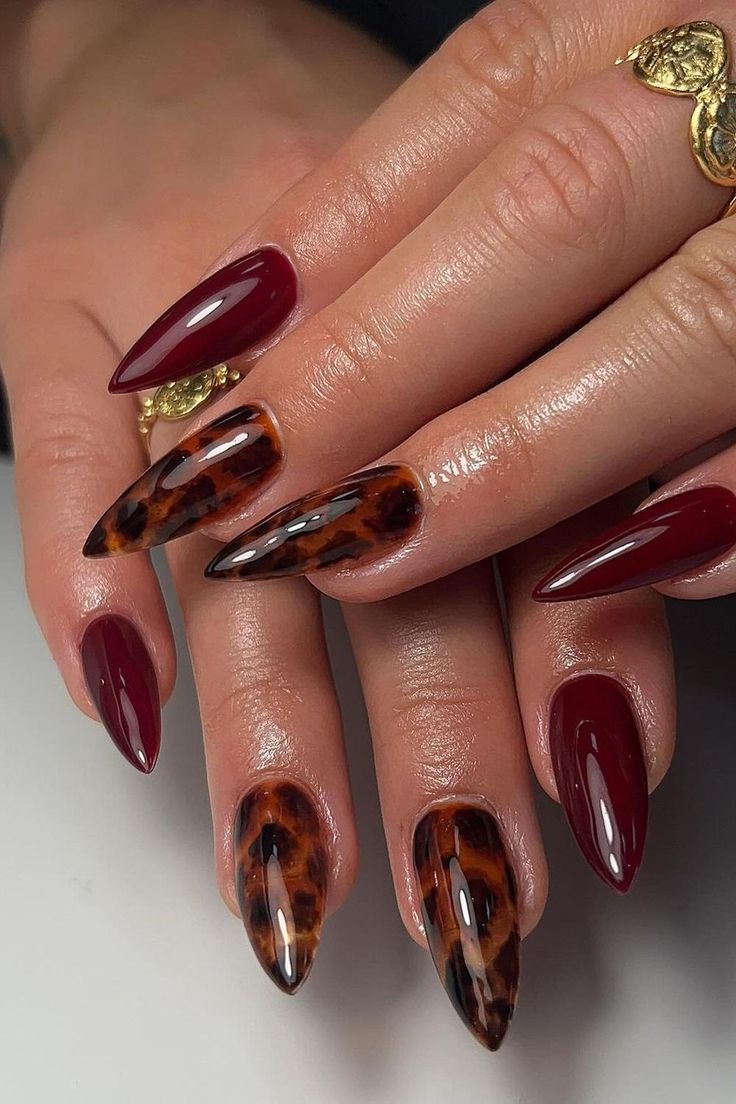 Striking Elongated Stiletto Nails in Rich Burgundy and Tortoiseshell Patterns for a Chic Sophisticated Look.