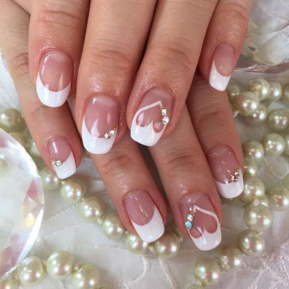 Chic French Manicure with Heart Tips and Glamorous Rhinestones on Soft Beige Base.