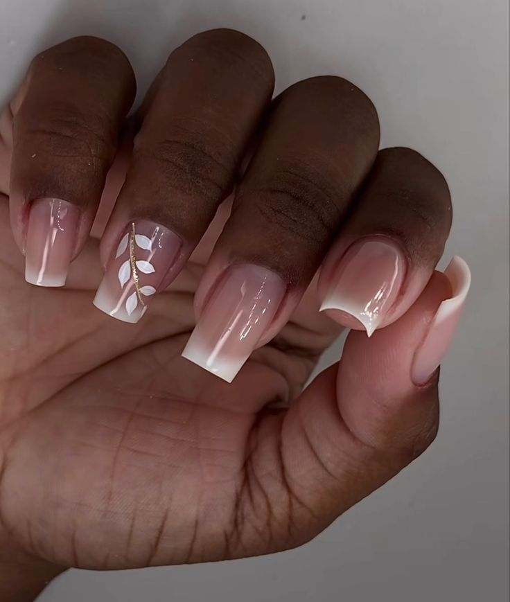 Chic Elegant Nail Design: Soft Pink French Tips with Whimsical Accent Leaf Pattern.