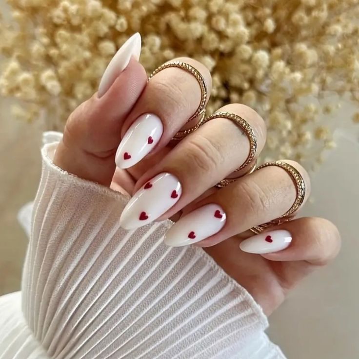 Chic Almond-Shaped White Nails with Red Heart Accents for a Romantic Touch.