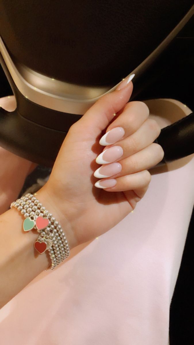 Chic French Tip Nail Design Paired with Colorful Heart Charm Bracelet for Timeless Elegance.