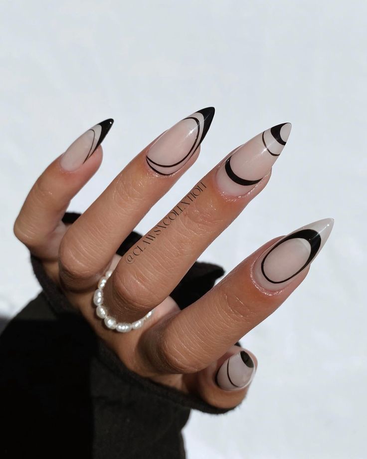 Chic Nude and Black Stiletto Nails with Elegant Geometric Designs and Pearl Accent.