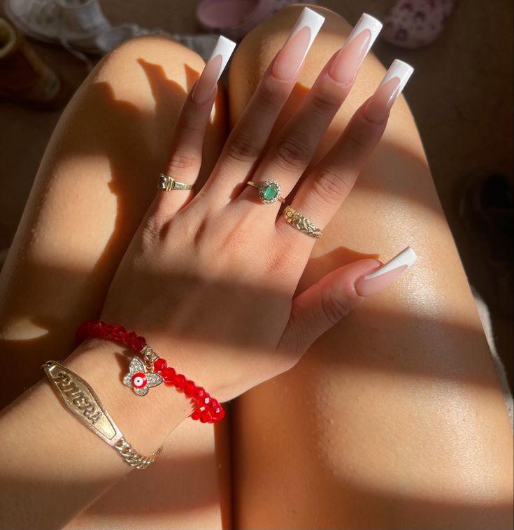 Chic French Tip Acrylic Nails Enhanced by Elegant Jewelry and Warm Sunlight.