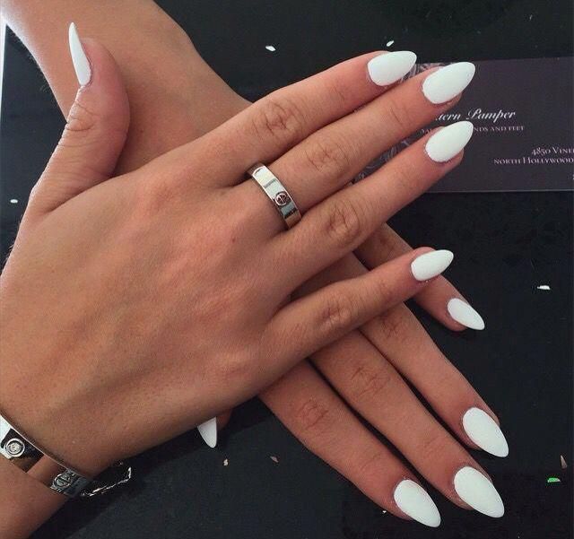 Sophisticated Almond-Shaped White Nails: A Versatile Look Enhanced by Silver Rings.