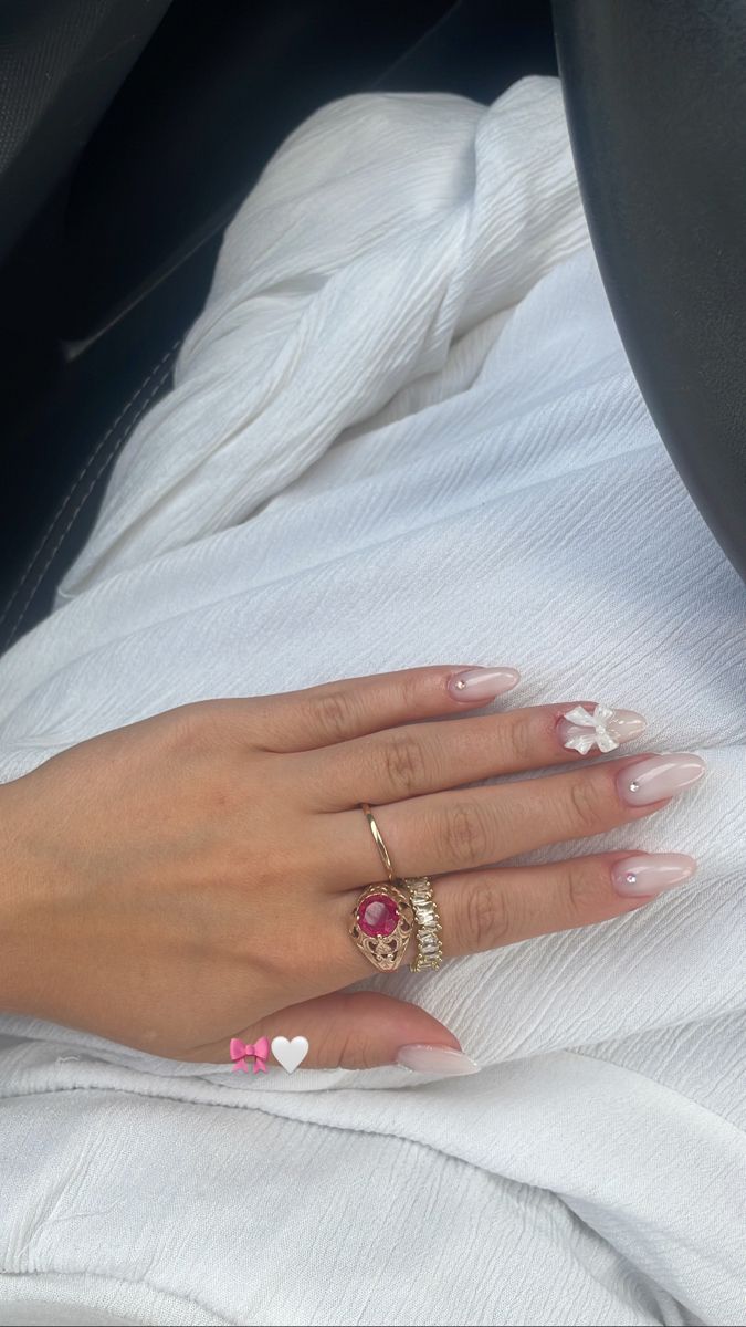 Elegant Soft Pink Nail Design with Whimsical Accents and Statement Ring Pairing