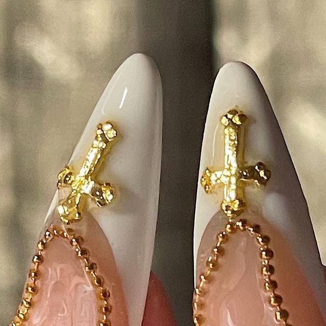 Sophisticated Glossy White and Pink Nail Design with Golden Cross Embellishments