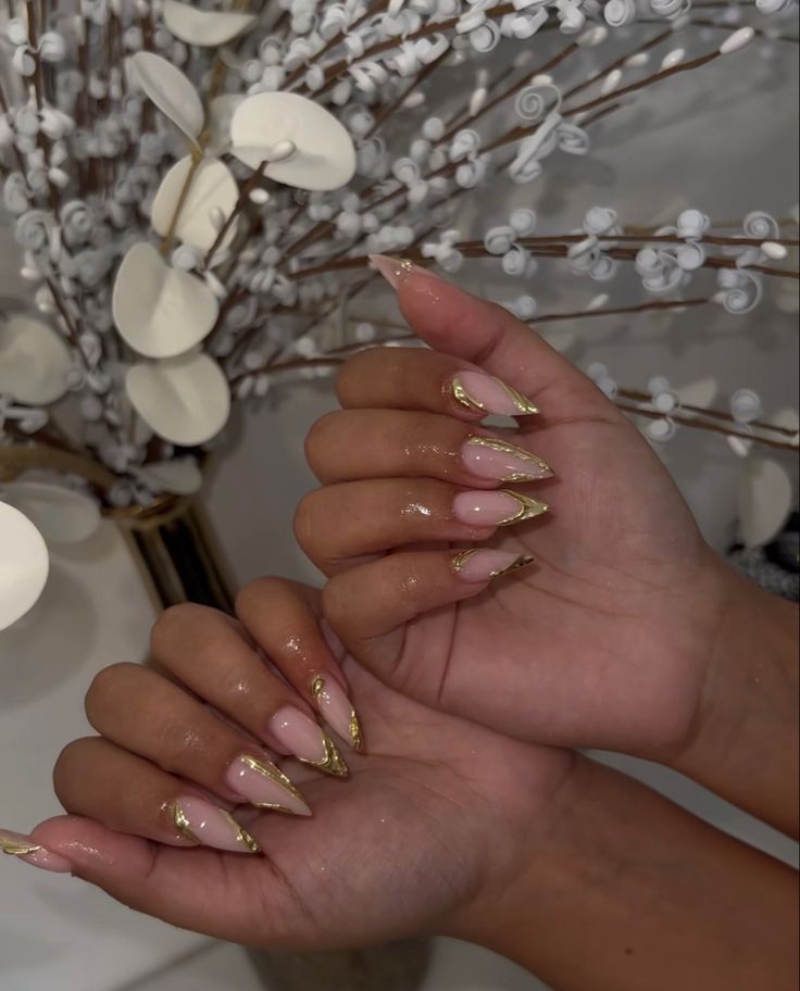 Chic Almond-Shaped Nail Design: Soft Pink Base with Striking Gold Tips.