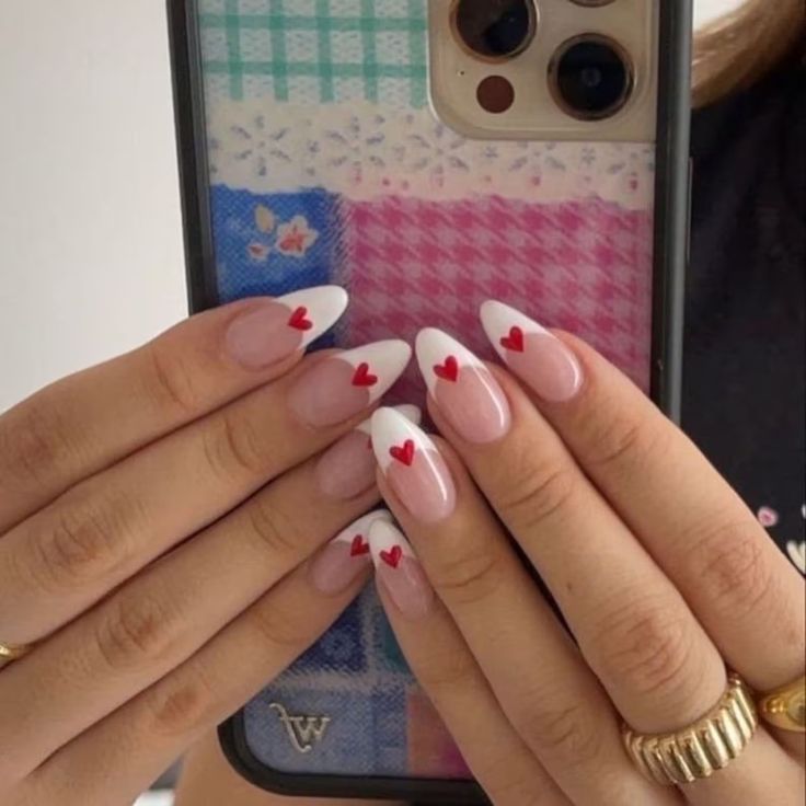 Charming Pink Nail Design with Elegant White French Tips and Adorned Red Hearts for a Playful, Romantic Look.