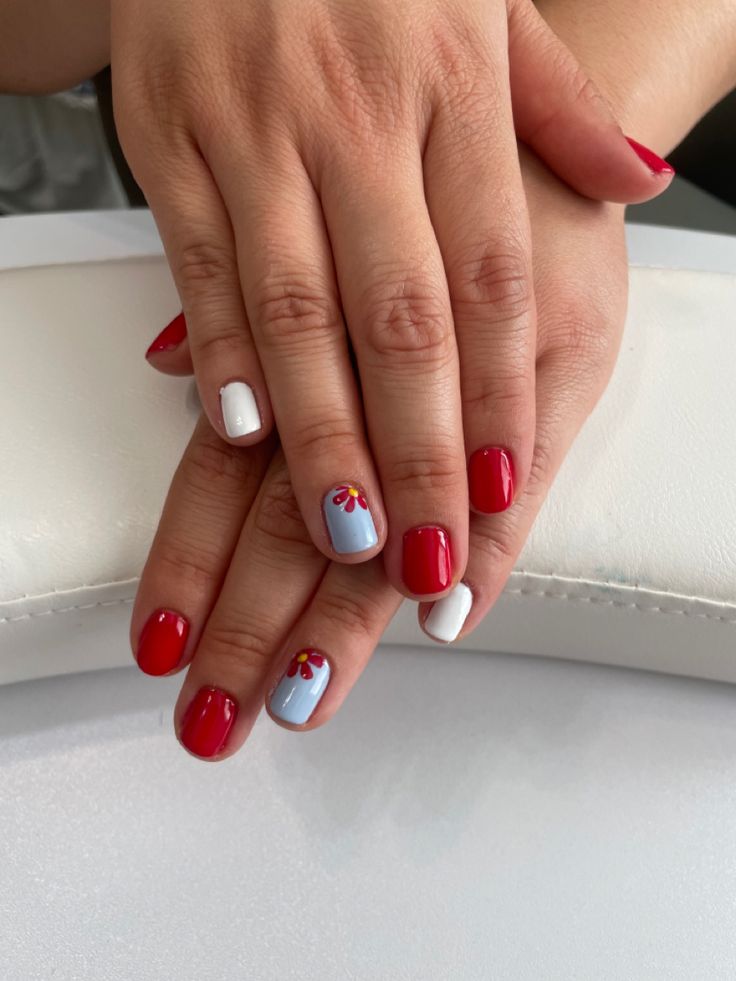 Vibrant Red, White, and Pastel Blue Nail Design with Playful Floral Accents.