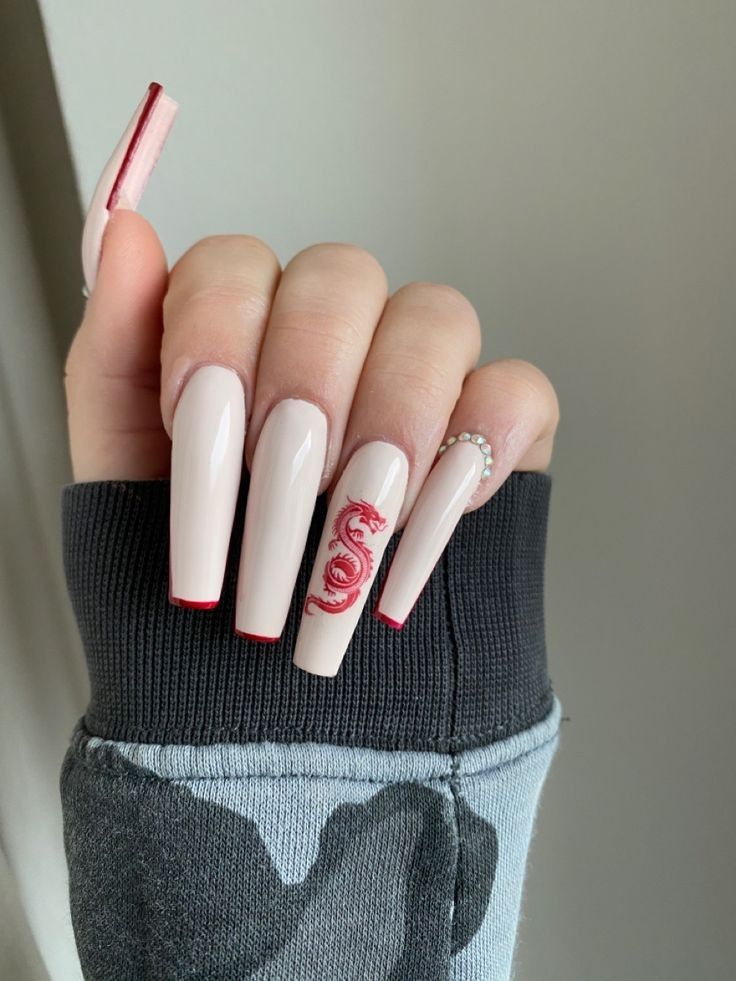 Chic Long Nude Nails with Striking Red Tips and Glamorous Gem Accents