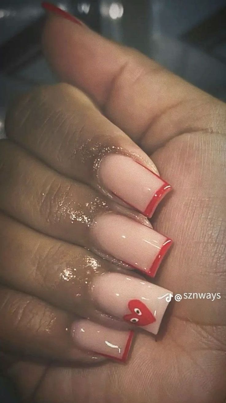 Elegant Nude Nail Design with Bold Red Tips and Heart Accent.