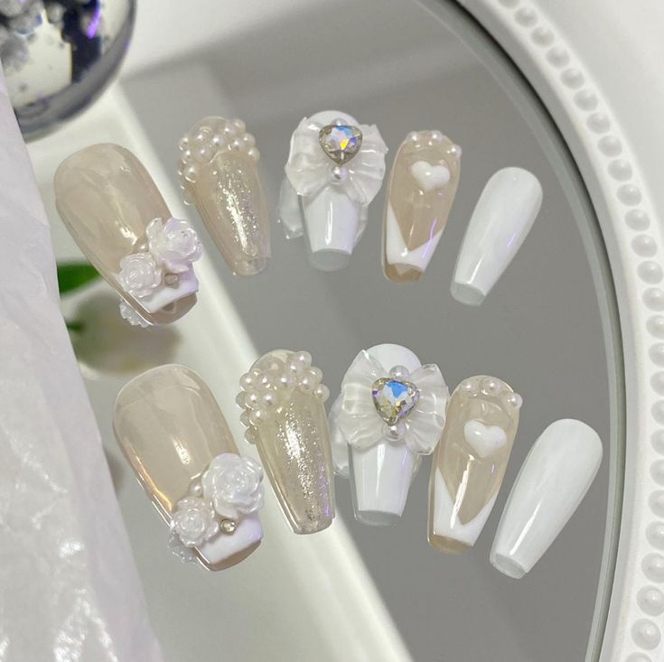 Sophisticated Nail Design with Nude and White Tones, Embellished with Pearls, Floral Motifs, and Sparkling Rhinestones.