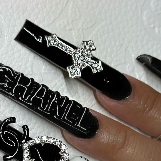 Chic Black Nail Design with Glossy Finish and Edgy Silver Cross Accents.