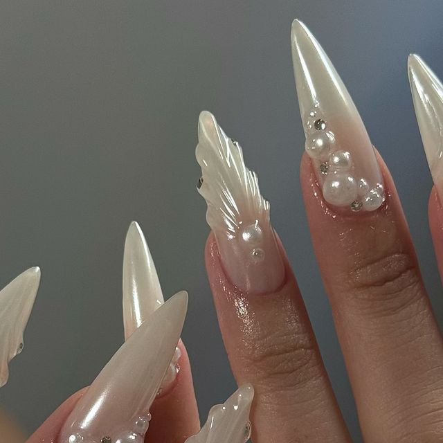 Luxurious Stiletto Nail Design with Pearlescent Finish and Intricate Leaf Motifs.