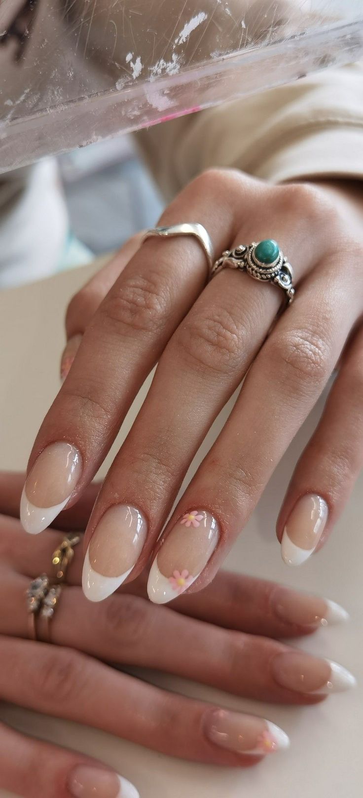 Chic French Manicure with Floral Accents and Stylish Rings