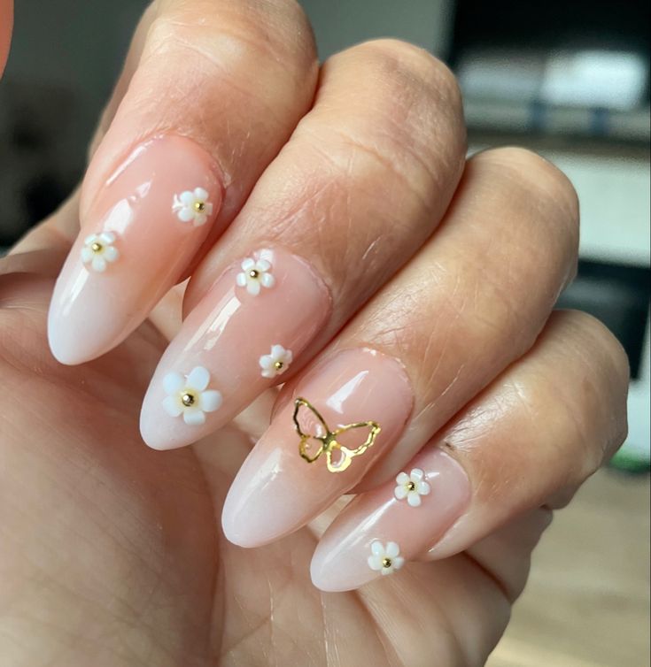 Charming Floral Nail Art: Soft Pink Ombre with Daisy Accents and Gold Butterfly Enhancements.