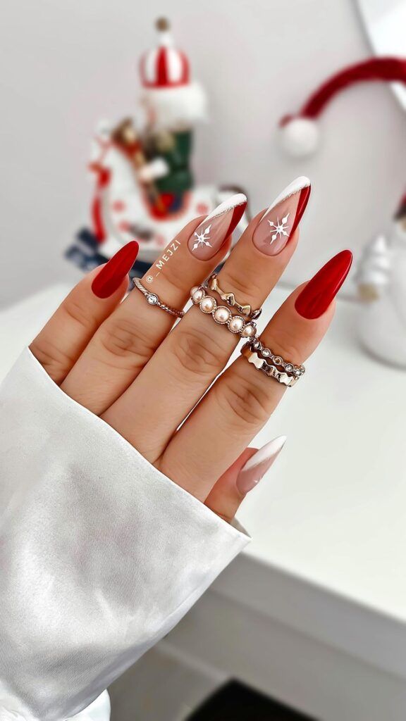 Chic Festive Nail Design: Deep Red and Nude with Snowflake Accents.