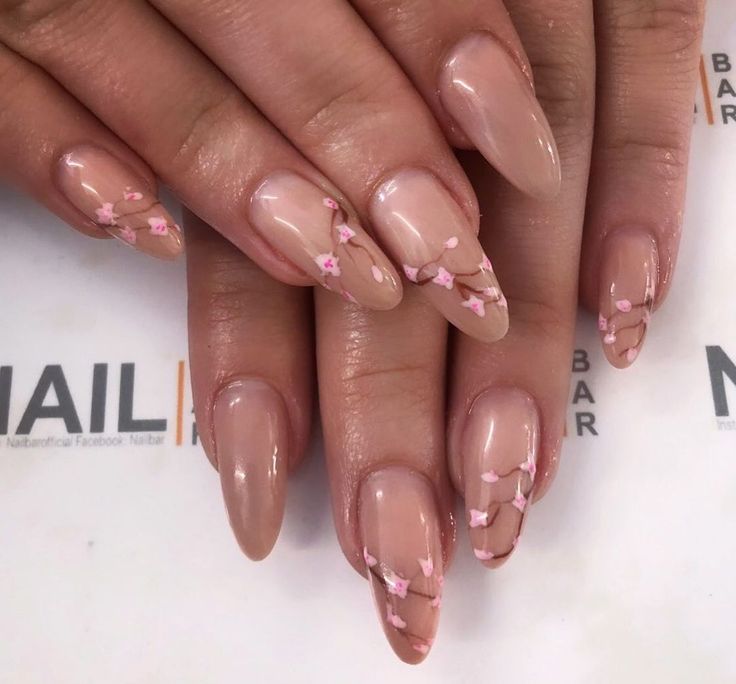 Elegant Nude Manicure with Delicate Floral Accents and Almond Shaping.