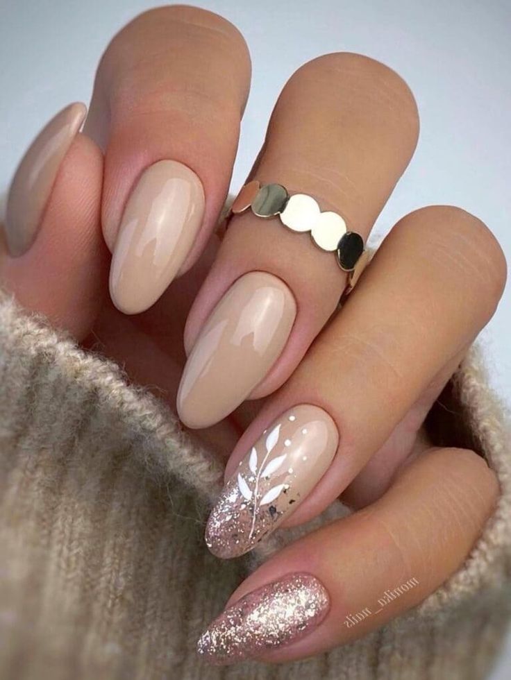 Chic Nude Nail Design with Glitter Accents and Sophisticated Leaf Patterns.