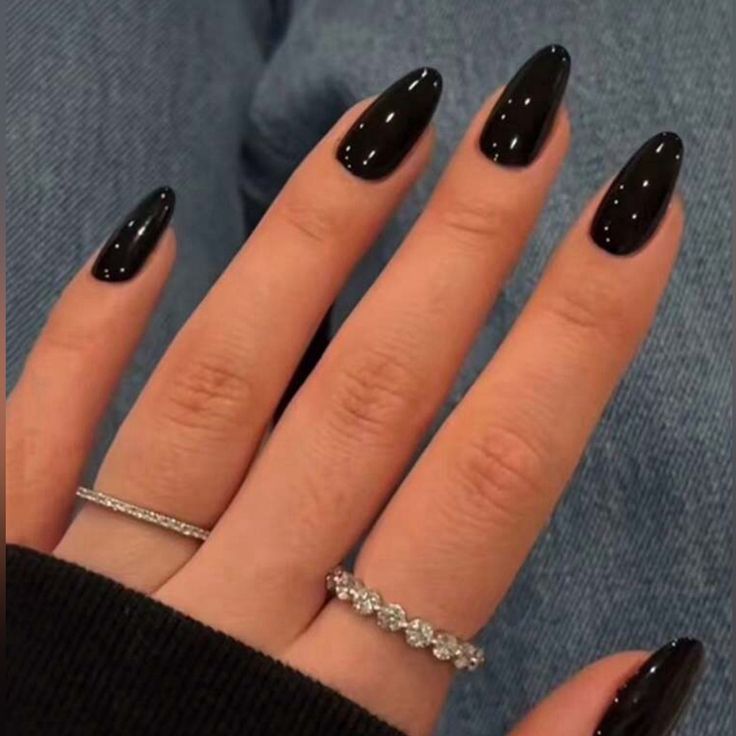 Sophisticated Black Almond-Shaped Nail Design with Glossy Finish and Delicate Rings.