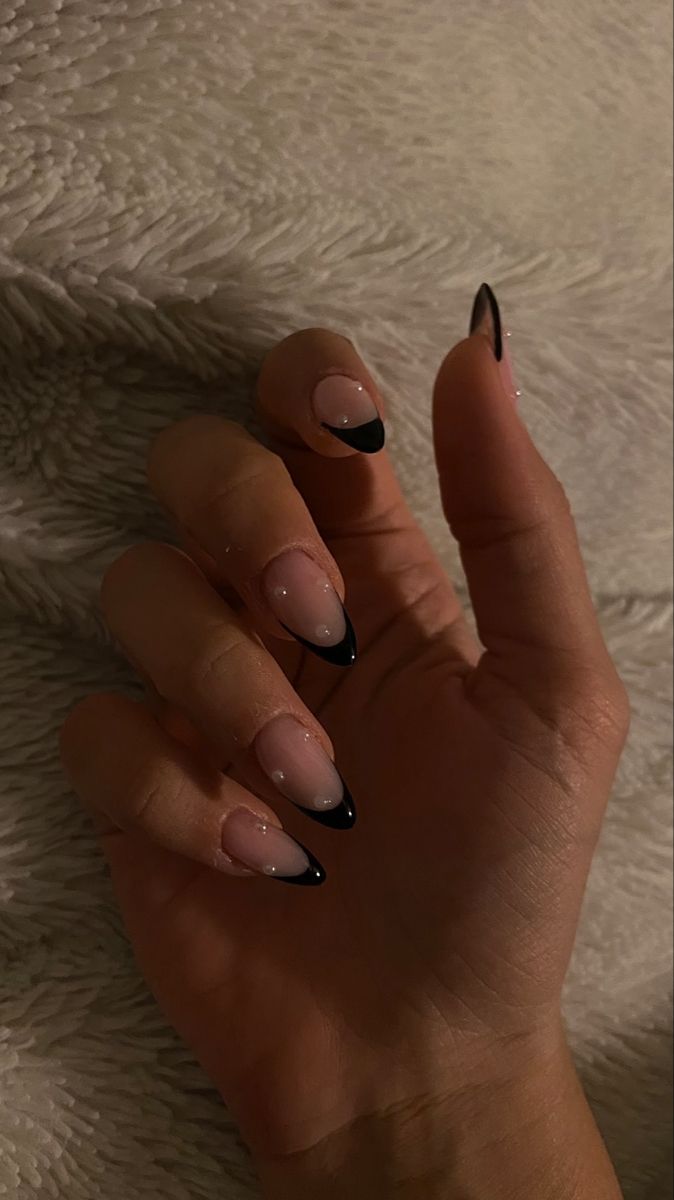 Chic French Tip Nail Design: Nude Base with Striking Black Tips and Elegant Embellishments.