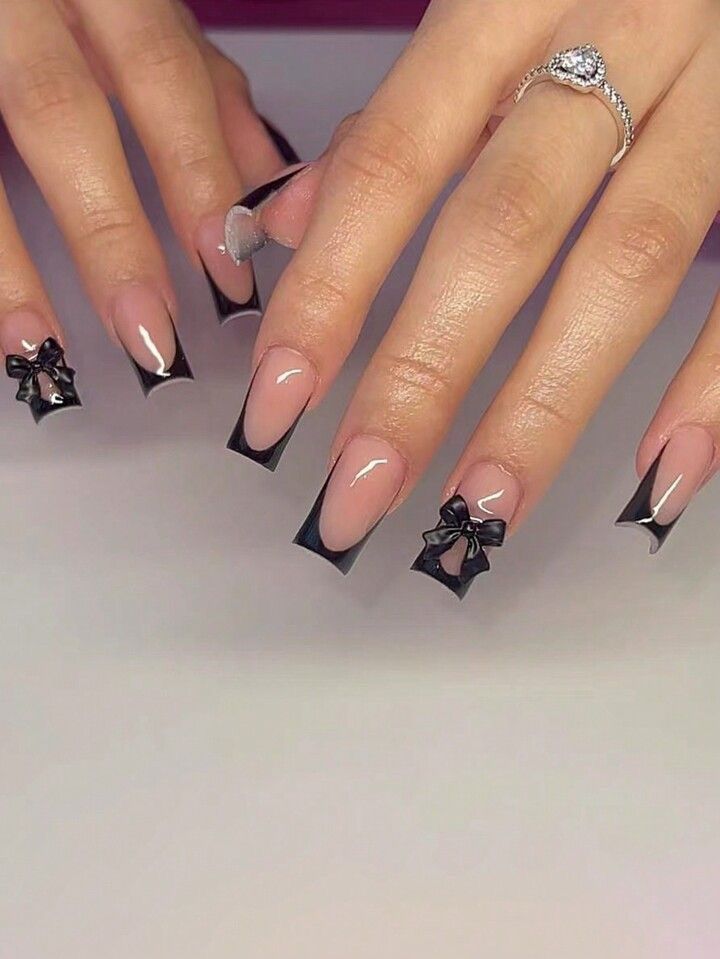 Chic Nude and Black Nail Design with Delicate Bows and Glossy Finish.