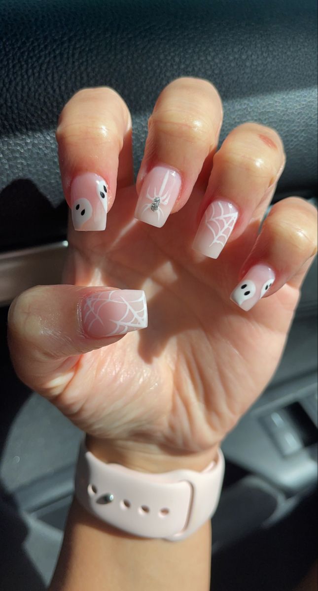 Playful Pastel Halloween Nail Design with Ghost Motifs and Spider Web Patterns.