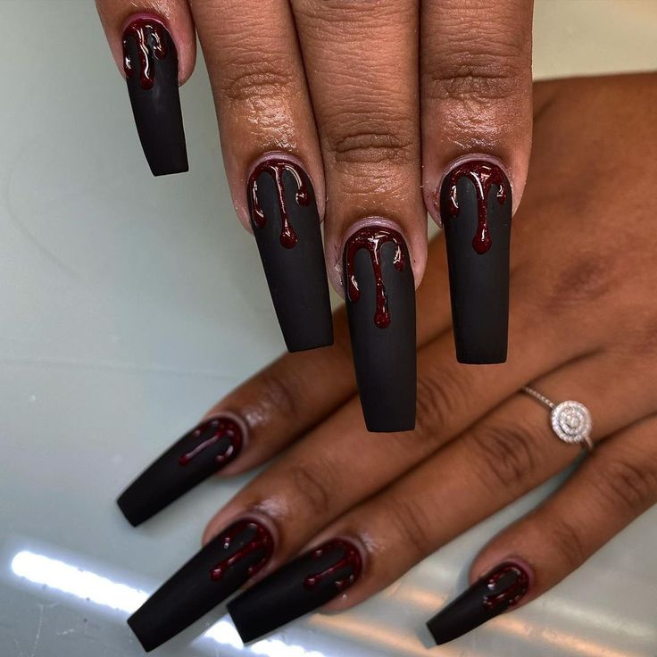 Bold Matte Black Nails with Glossy Red Drips for a Striking Statement Look.