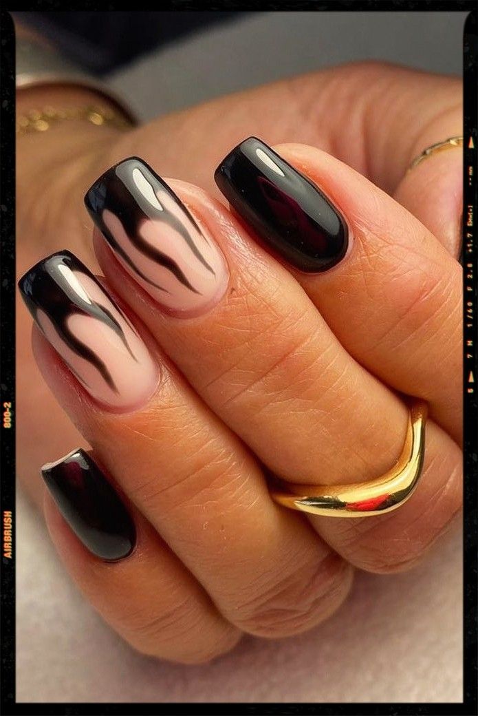 Bold Nail Design: Glossy Black and Nude Shades with Dramatic Flame Patterns.