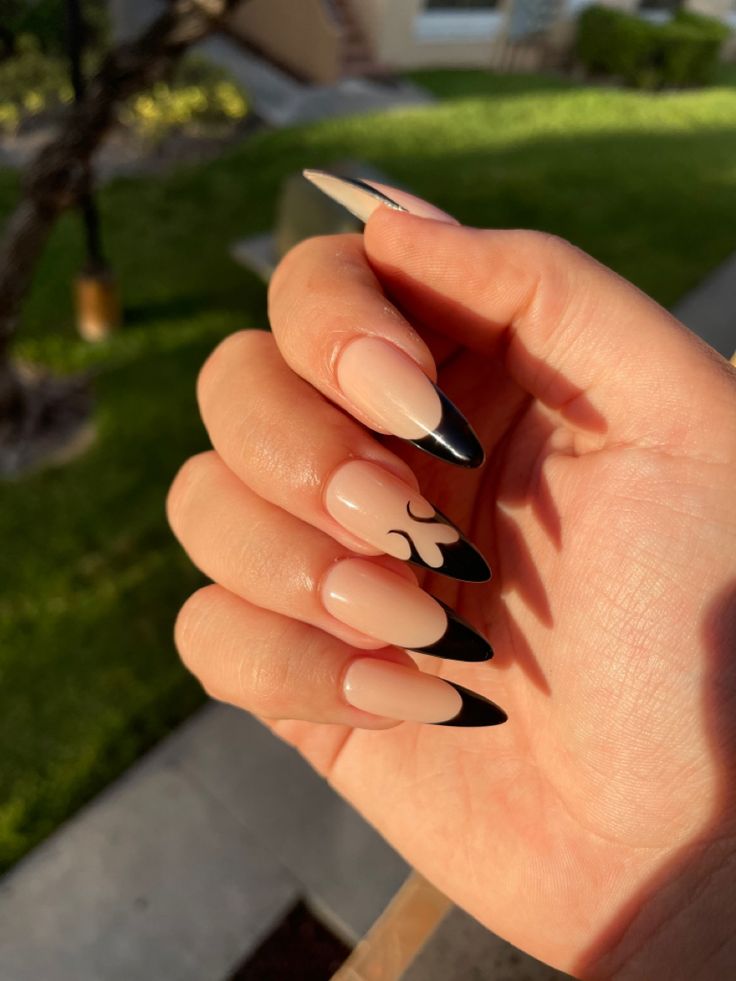 Elegant Almond-Shaped Nails: Chic Nude Base with Sharp Black Tips and Minimalist Swirl Design.