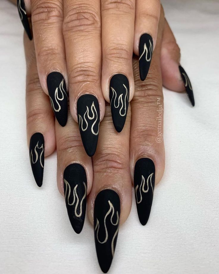 Edgy Black Matte Nails with Glamorous Gold Flame Designs for Bold Statement Art.