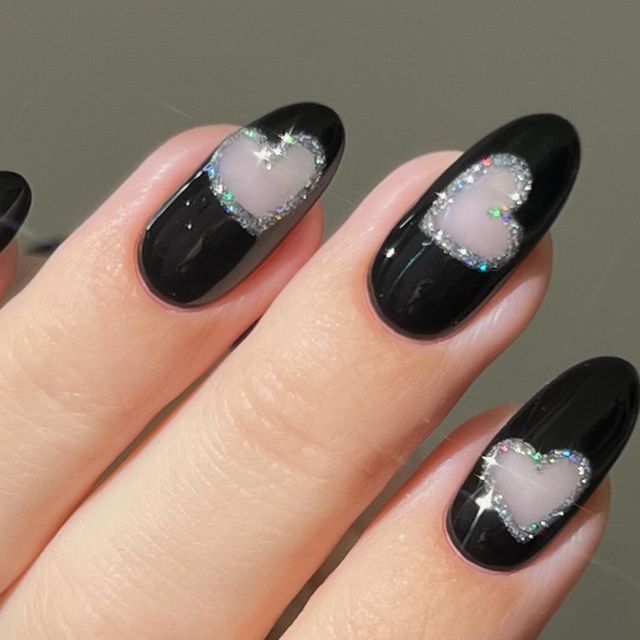 Romantic Black Nail Design with Heart Shapes and Shimmering Rhinestones.