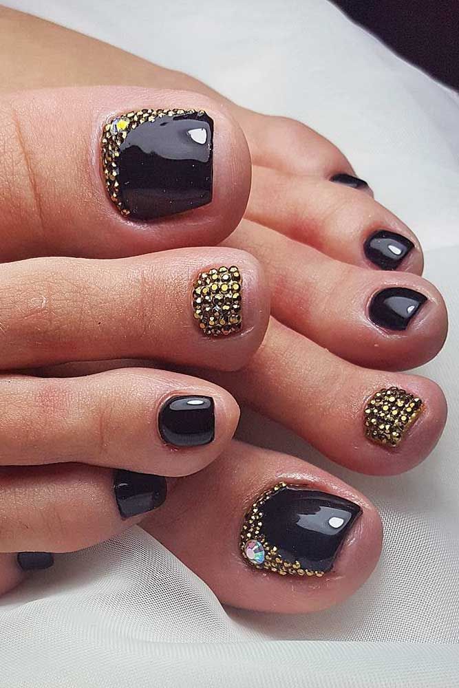 Chic Black and Gold Nail Design with Glossy Finish and Intricate Embellishments.