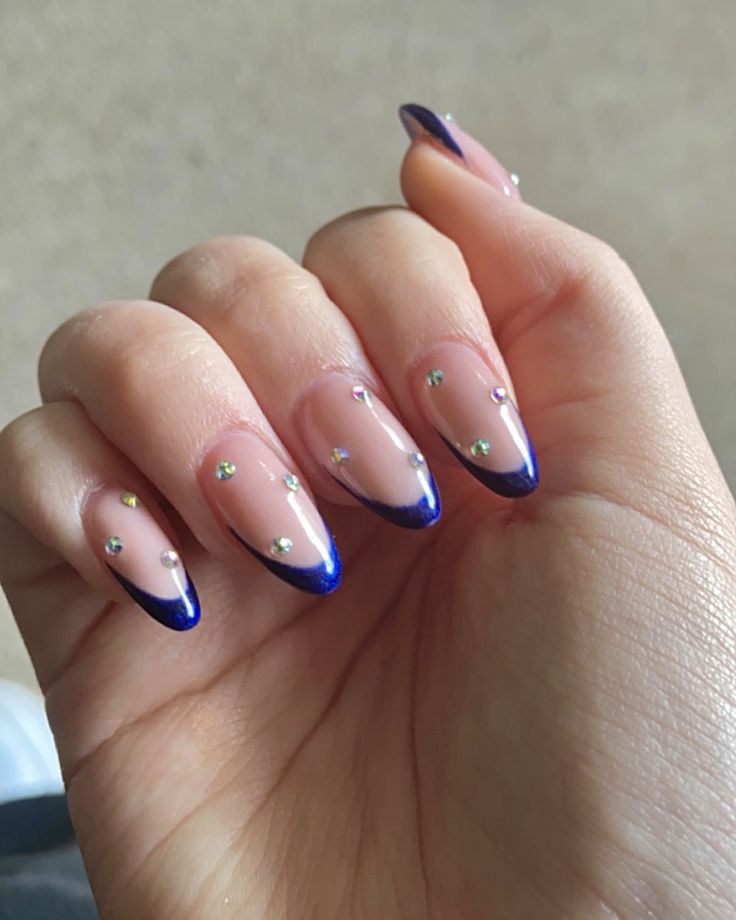 Sophisticated Nail Design: Sheer Nude Base with Striking Dark Blue Tips and Sparkling Rhinestones.