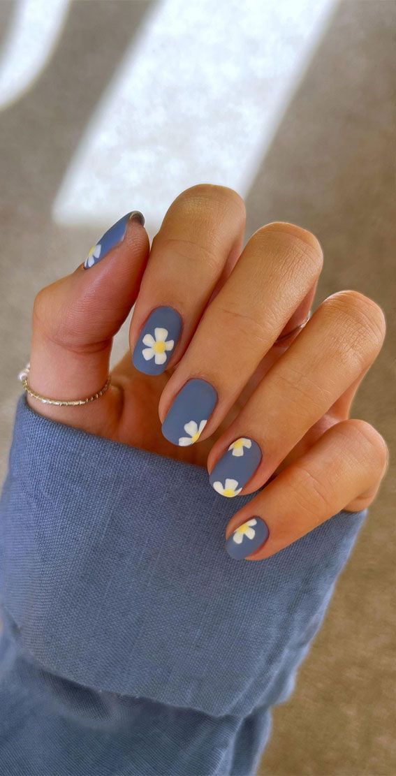 Elegant Floral Nail Design: Muted Blue Base with White Daisies for a Chic Spring Look.