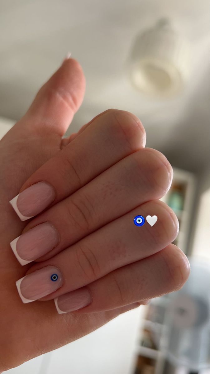 Sophisticated French Tip Nail Design with Playful Blue Eye Accents