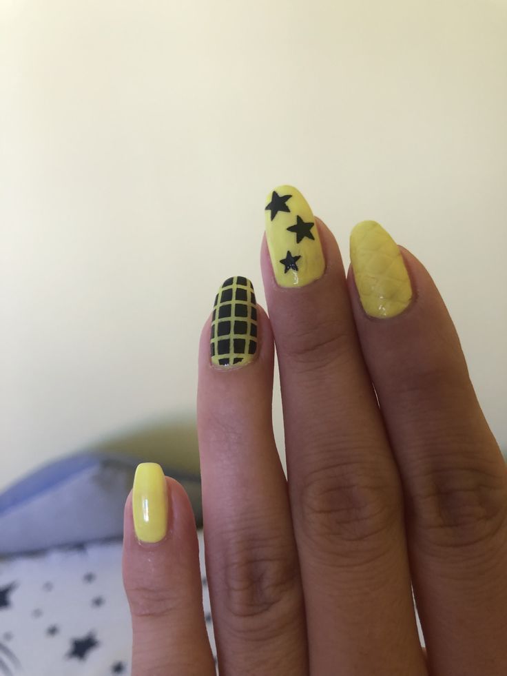 Vibrant Yellow Nail Design with Playful Black Accents and Patterns.