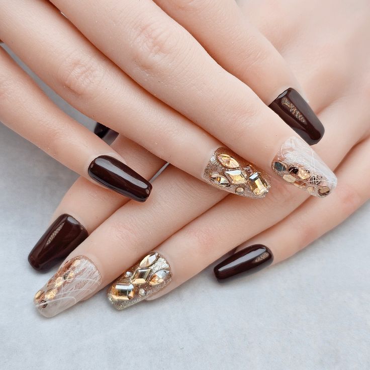 Chic Deep Brown Nail Design with Gold Accents and Lace Patterns for Special Occasions.