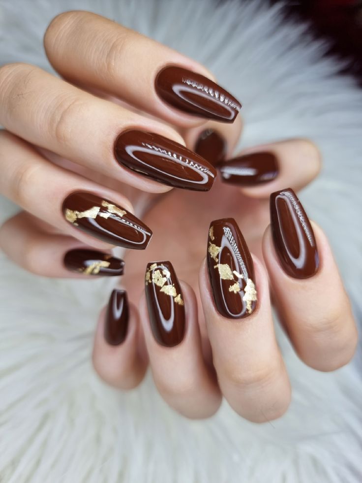 Sophisticated Brown Almond Nails with Gold Accents: A Harmonious Blend of Elegance and Boldness.