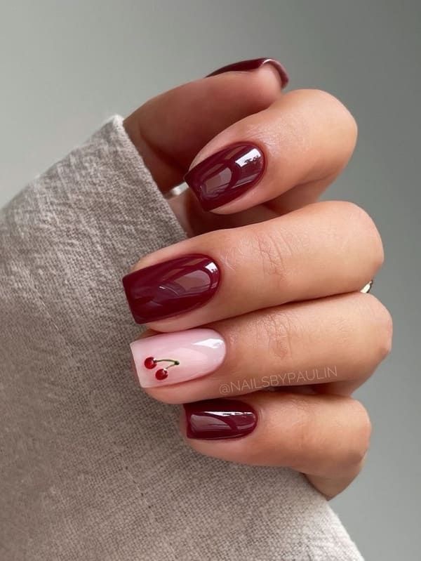 Chic Deep Burgundy and Soft Pink Nail Design with Whimsical Cherry Accent.