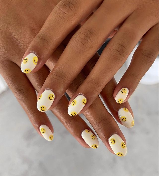 Playful Yellow Smiley Face Nail Design on White Base for a Joyful Manicure.