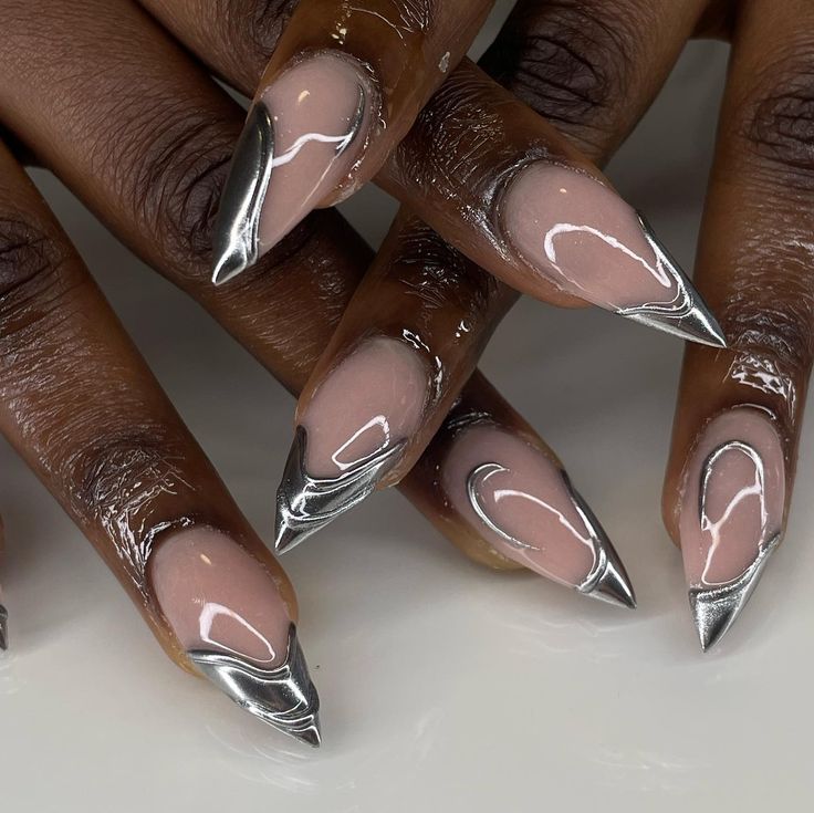 Edgy Stiletto Nails: Nude Base with Metallic Silver Tips and Fluid Line Accents.