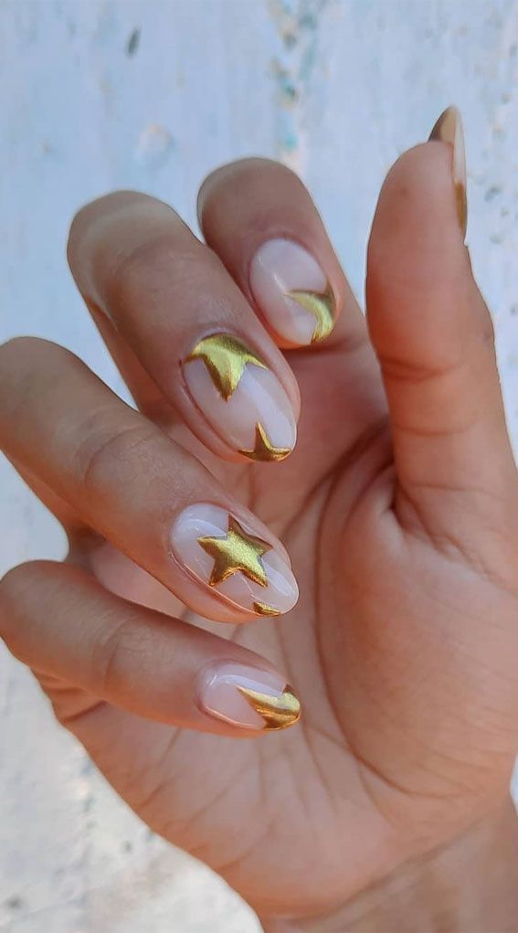 Chic Nail Design: Clear Base with Bold Gold Accents and Playful Heart and Star Motifs