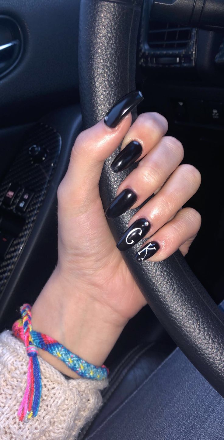 Chic Black Glossy Nails with Personalized Accents and Playful Bracelet Complement.